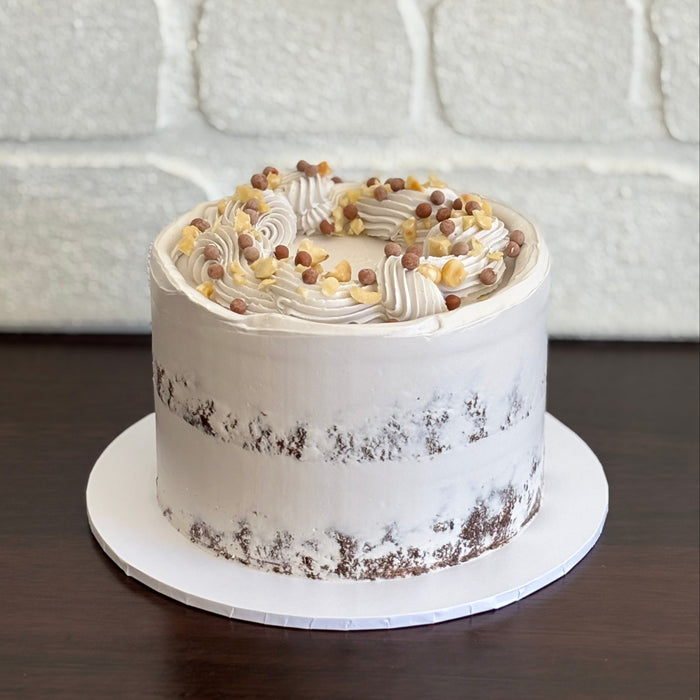 Chocolate hazelnut semi naked cake decorated with hazelnut pieces and chocolate crispearls