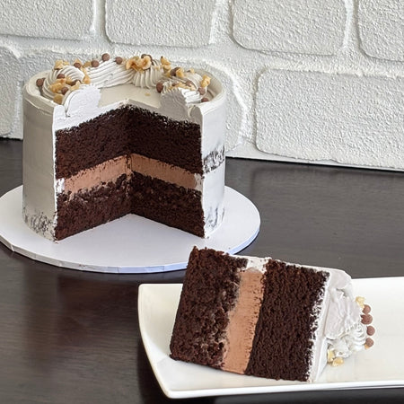 Chocolate hazelnut semi naked cake decorated with hazelnut pieces and chocolate crispearls