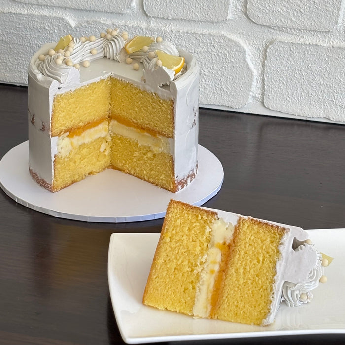 lemon mud cake layered with white chocolate ganache and lemon curd. Finished with a semi naked swiss meringue buttercream, white crisp pearls and fresh lemon pieces