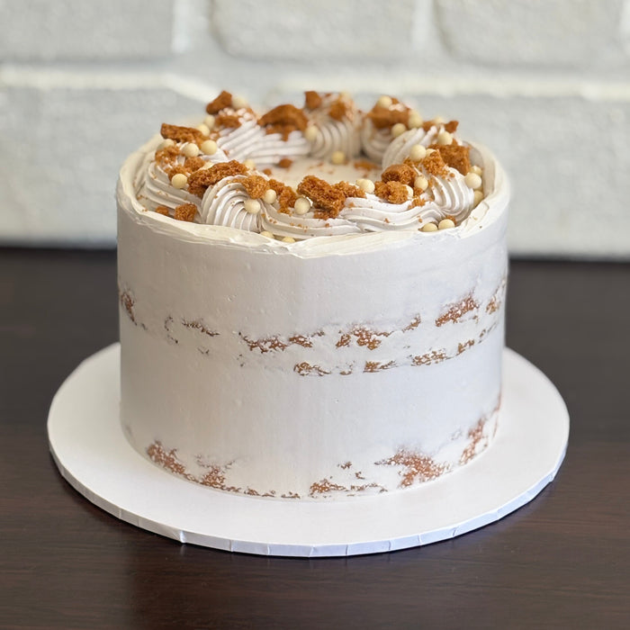 white mud cake layered with biscoff ganache and finished with a semi naked swiss meringue buttercream. Decorated with biscoff pieces and white crispearls