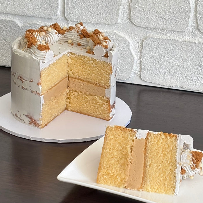white mud cake layered with biscoff ganache and finished with a semi naked swiss meringue buttercream. Decorated with biscoff pieces and white crispearls