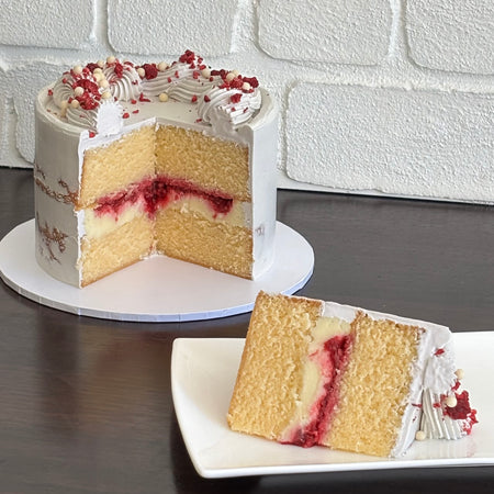white mud cake layered with white chocolate ganache, raspberry and raspberry sauce. Finished with swiss mernigue semi naked buttercream, freeze dried raspberry and white crispearls
