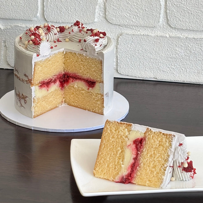 white mud cake layered with white chocolate ganache, raspberry and raspberry sauce. Finished with swiss mernigue semi naked buttercream, freeze dried raspberry and white crispearls